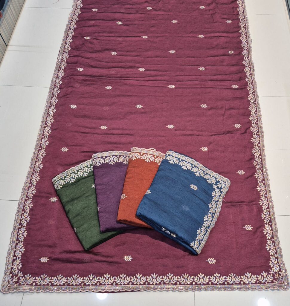 Elegant embroidered saree collection in green, purple, rust orange, and blue colors, displayed on a maroon base saree. Each saree features fine white floral embroidery with a detailed lace border. Perfect for party wear sarees, festive sarees, traditional functions, and wedding occasions.